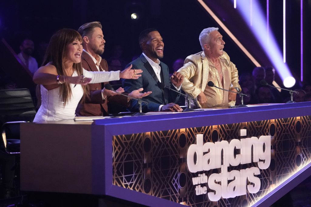 Michael Strahan sits with Carrie Ann Inaba, Derek Hough and Bruno Tonioli on the DWTS judges desk