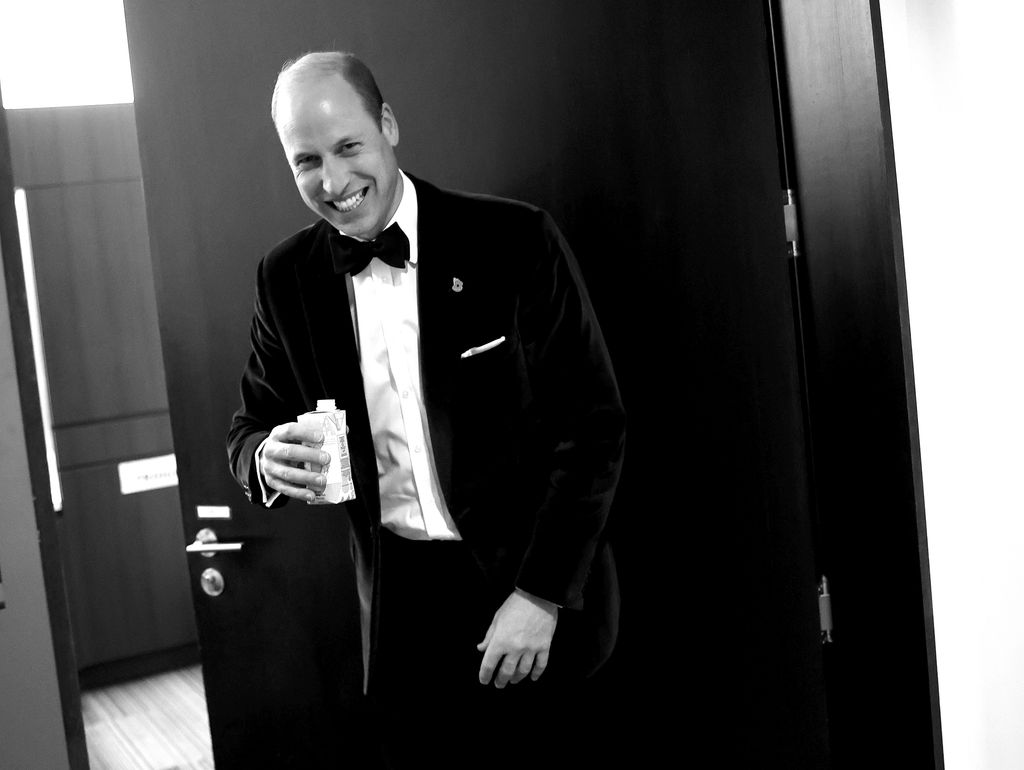 Prince William laughing and holding a drinks carton