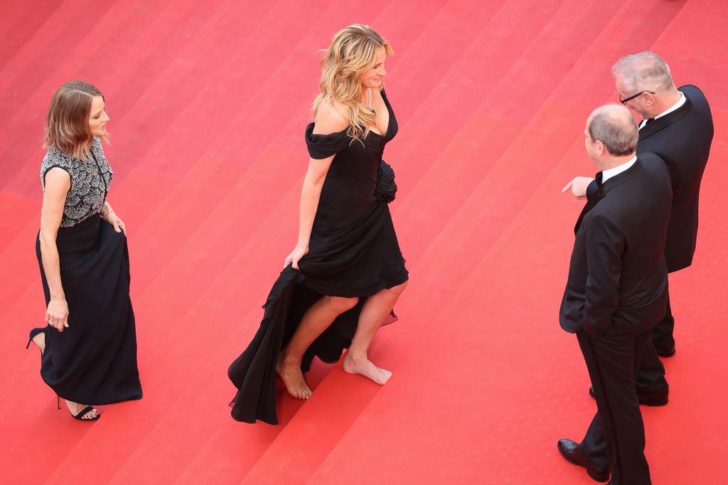 Julia Roberts walks barefoot upon her arrival as producer Jodie Foster smiles at the 'Money Monster' premiere during the 69th annual Cannes Film Festival at the Palais des Festivals on May 12, 2016 in Cannes, France