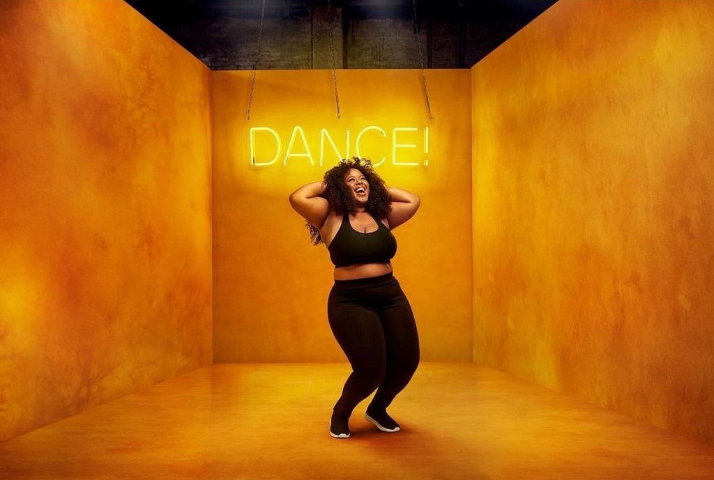 Black woman in black sports attired dancing in a studio