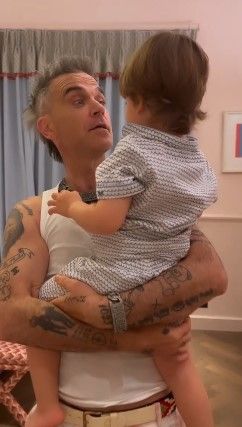 Robbie Williams showing off tattoos holding son Charlie