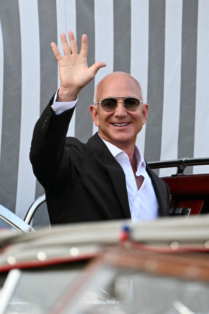 Amazon's founder Jeff Bezos waves as he gets on a taxi boat at the Aman Hotel 