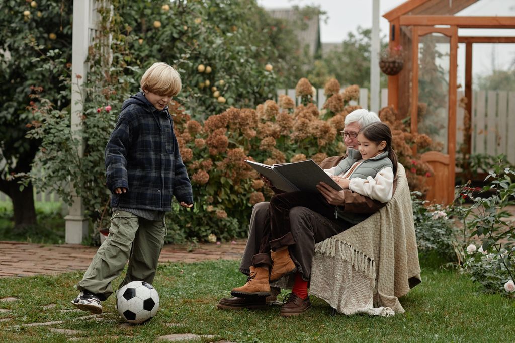 Un grand-père lisant à sa petite-fille tandis qu'un petit-fils a un football