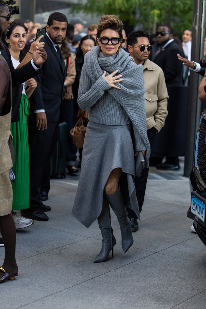 Lisa Rinna wears grey wrapped knit, asymmetric skirt, glasses outside Michael Kors during New York Fashion Week on September 10, 2024 in New York City