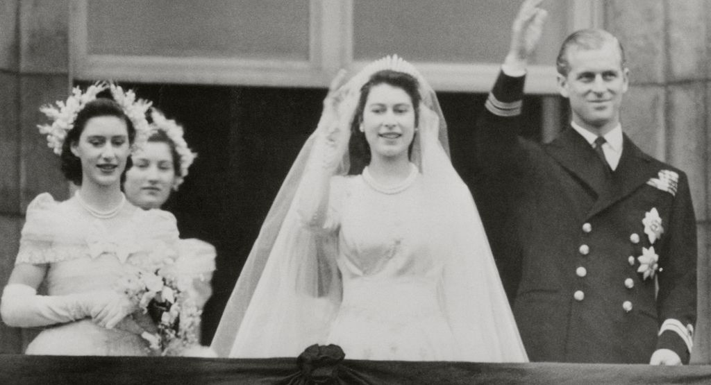 Newly-married Princess Elizabeth and Prince Philip wave from a balcony at Buckingham Palace next to bridesmaid Princess Margaret