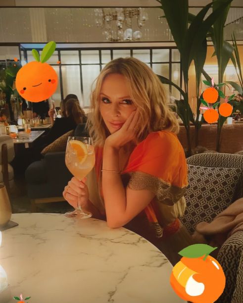 Kylie Minogue with orange drink in orange outfit