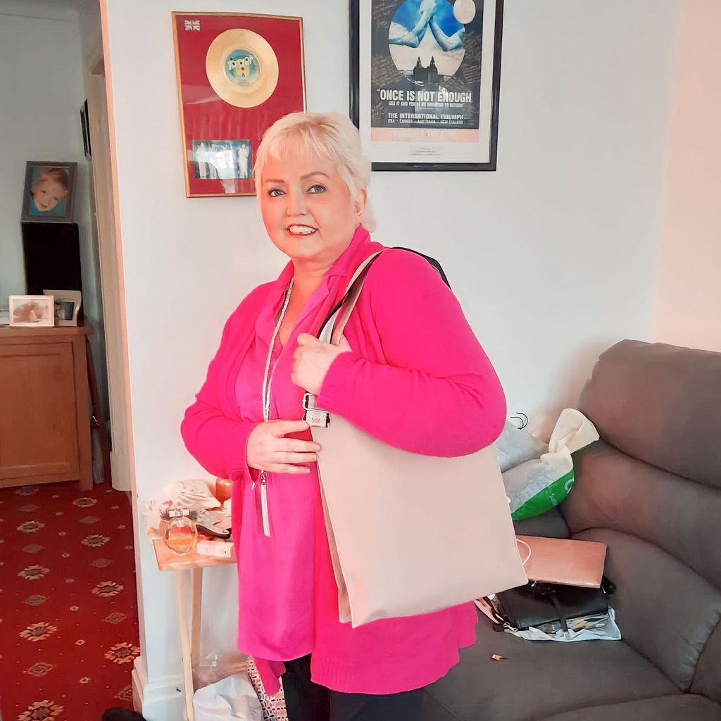 Linda Nolan smiling at home in a pink cardigan