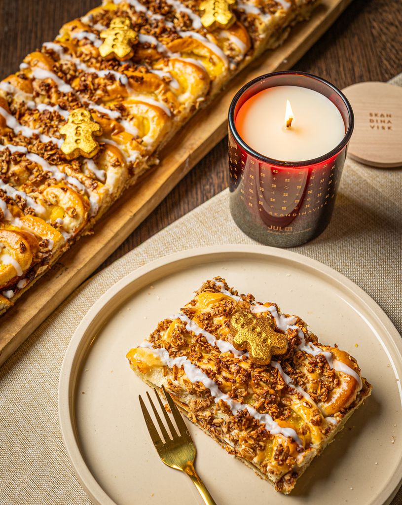 slice of gingerbread pastry on a table with a candle and fork