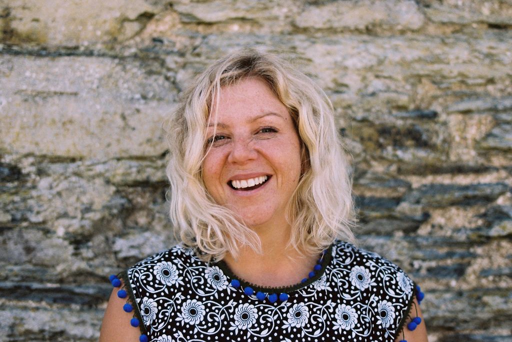 woman smiling against a stone wall