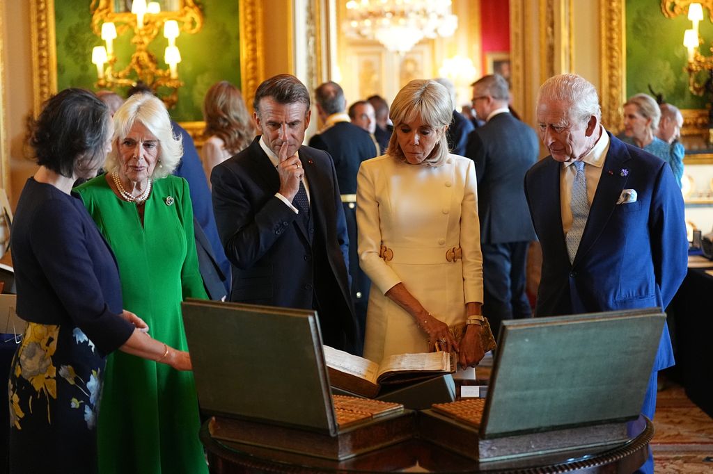 Queen Camilla, Emmanuel Macron, Brigitte Macron and King Charles looking at items in the royal collection