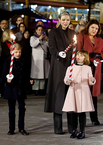 Prince Jacques holding a torch while Princess Charlene lights the one of Princess Gabriella