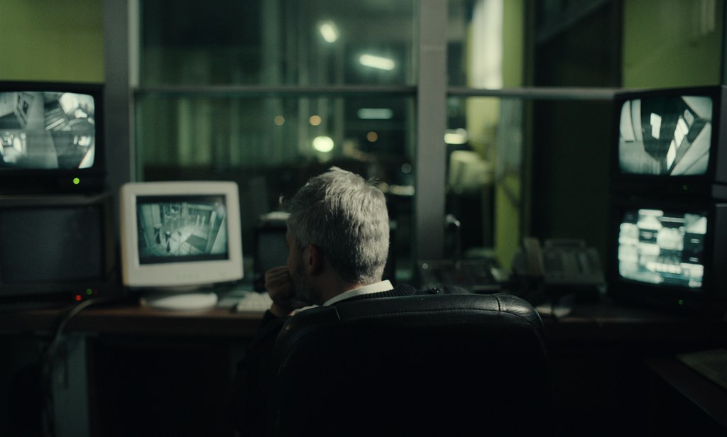 A man sits monitoring multiple screens