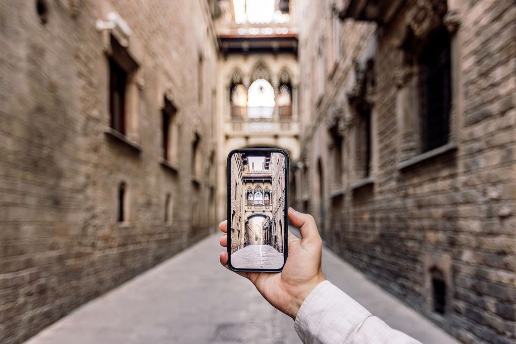 Tourist taking photo of a street in Gothic Quarter in Barcelona using smart phone, personal perspective view, Spain