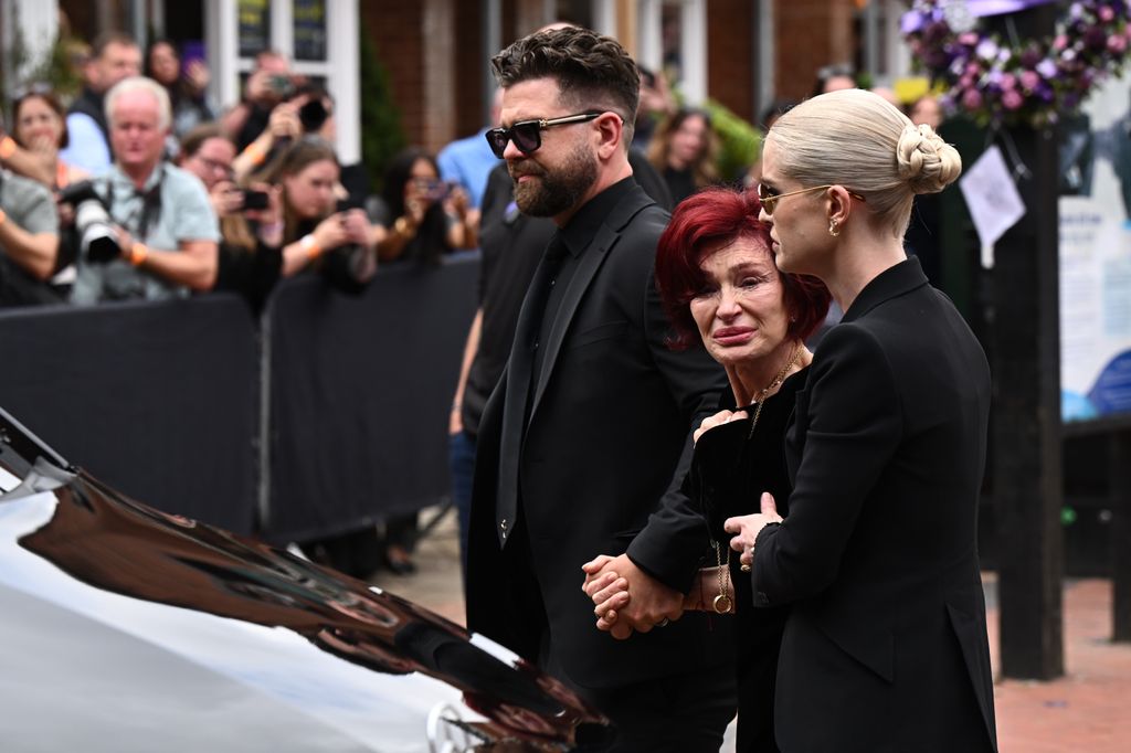 Jack Osbourne, Sharon Osbourne and Kelly Osbourne view tributes to the late Ozzy Osbourne from fans as his funeral cortege travels through his home city of Birmingham on July 30, 2025 in Birmingham