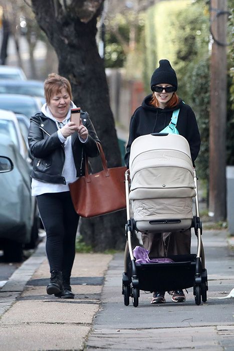Stacey Dooley walking her baby as her mum takes a photo on her phone