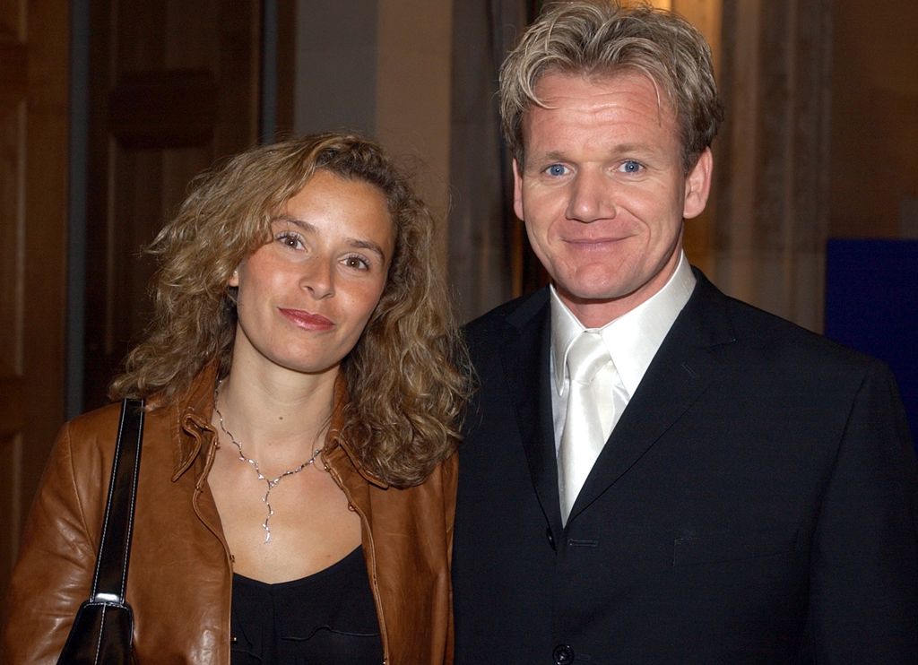 Chef Gordon Ramsay in a suit and his wife Tana in a brown leather jacket