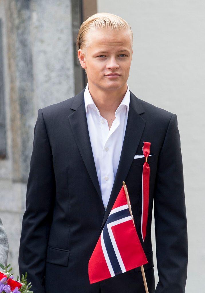 Marius Borg Hoiby in a suit in front of a Norwegian flag