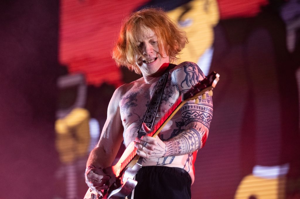 Danny on stage shirtless tattoos, playing guitar