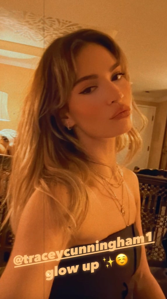 The image shows Lily James in a dimly lit setting, wearing a sleek black strapless top. Her blonde hair is styled in soft waves with curtain bangs, and she accessorizes with layered necklaces and subtle earrings. The text overlay reads "@traceycunningham1 glow up ✨☺️."