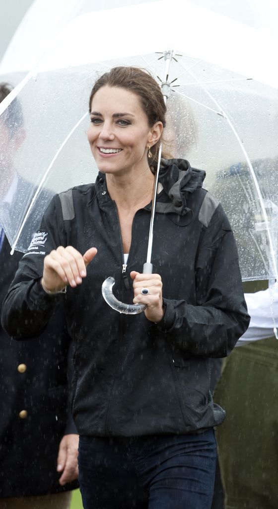 Princess Kate in a rain coat under an umbrella