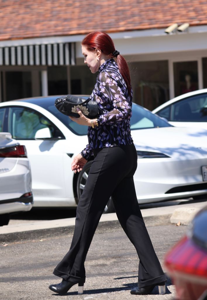 Priscilla Presley in a sheer floral blouse and flared trousers