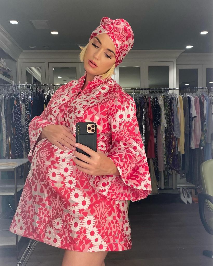 Katy Perry in a bold floral pink dress taking a mirror selfie