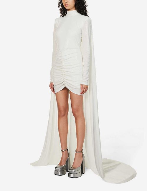 model wears an ivory mini dress with trailing cape