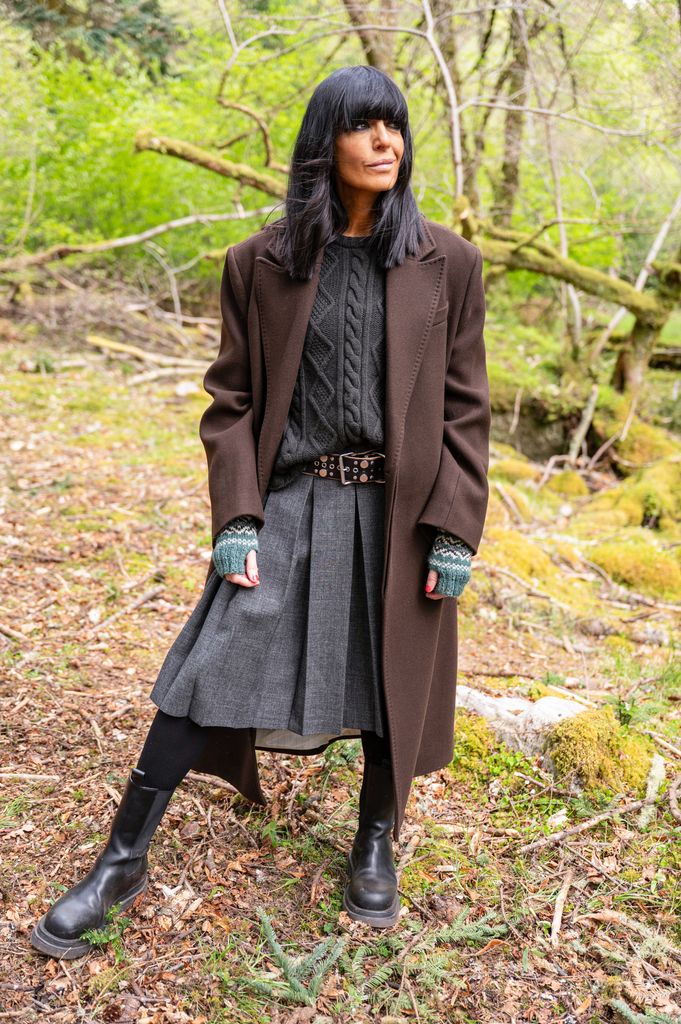 Claudia Winkleman wearing a brown coat, cable knit jumper and grey Prada skirt 