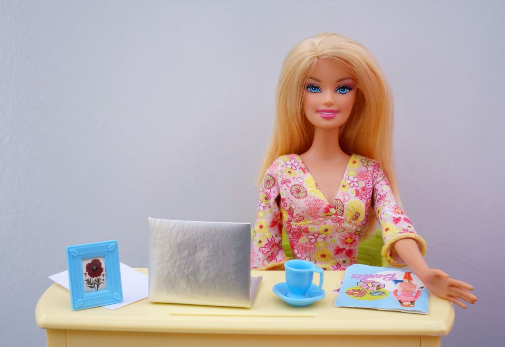 Barbie sitting at a desk with a laptop