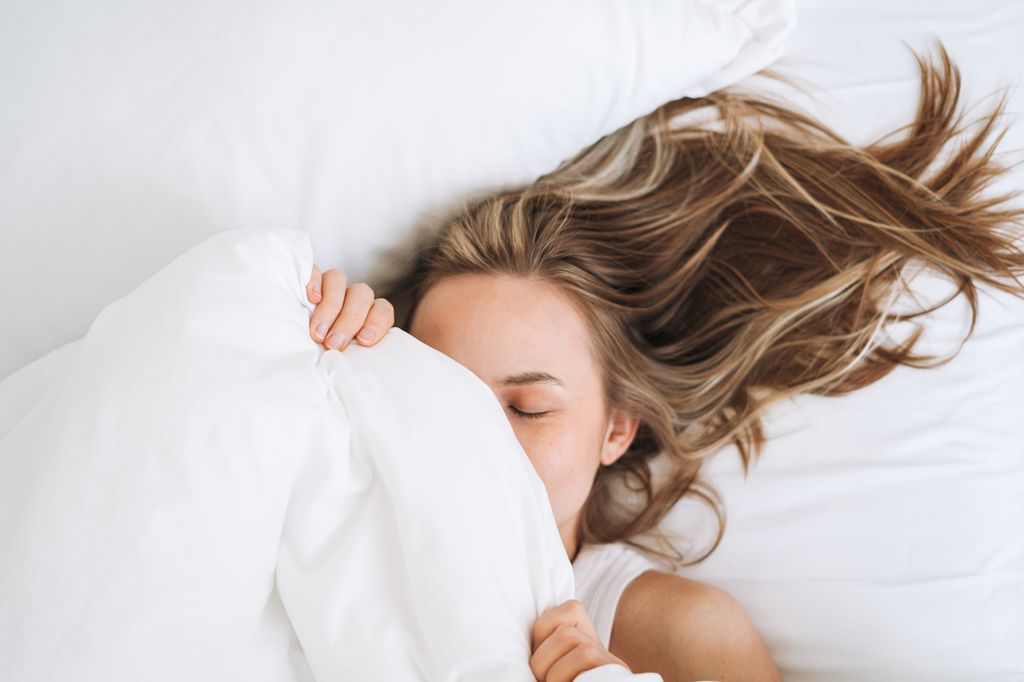 Young beautiful woman with long hair woke up in bed at home