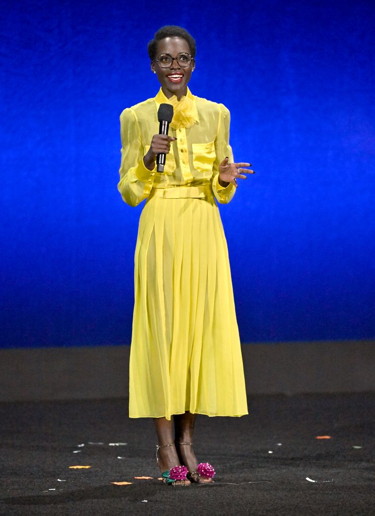 Lupita on stage in canary yellow