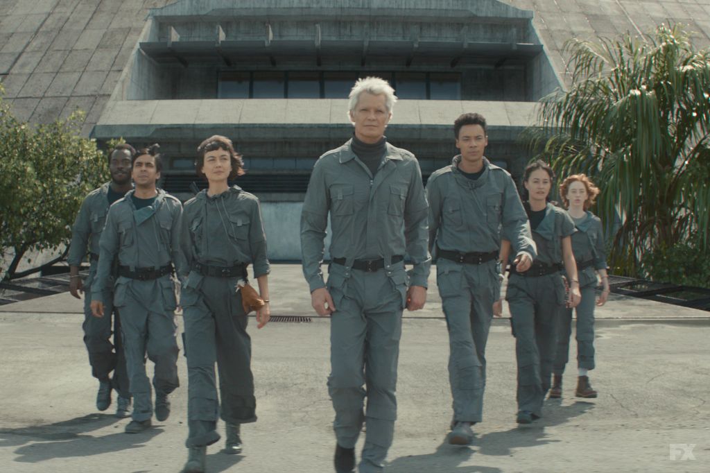 grou of people dressed in grey jumpsuits walking away from building