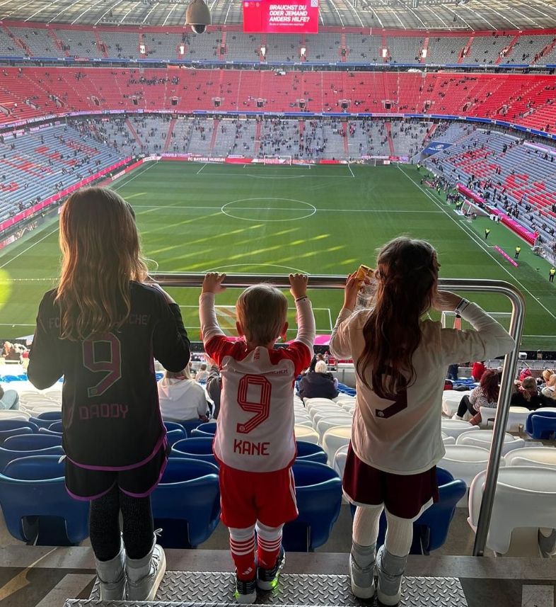 Three children looking out over an empty football field