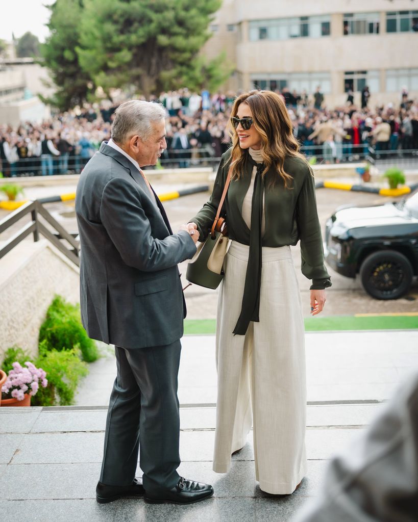 Queen Rania greeting man in linen trousers and khaki shirt