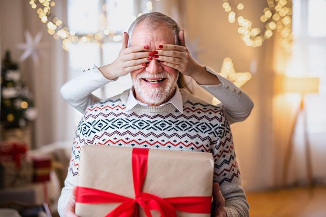 A man with his eyes blindfolded whilst holding a present