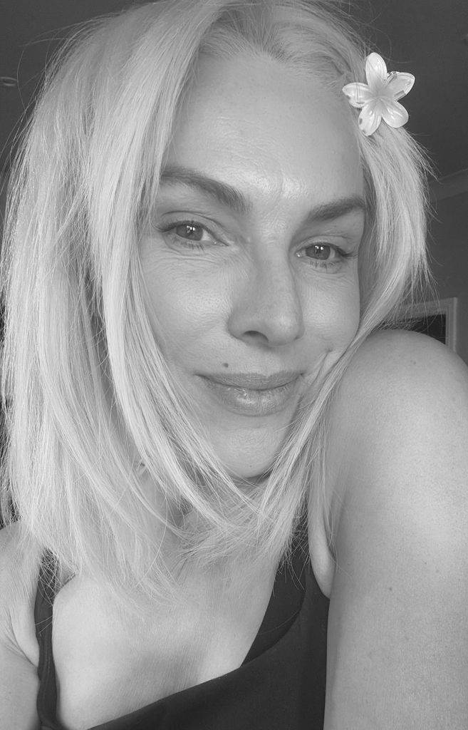 close up selfie of a blonde woman with a flower in her hair 