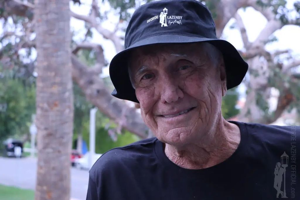 George Lazenby poses for a photograph wearing a bucket hat with his name on it, shared on Instagram