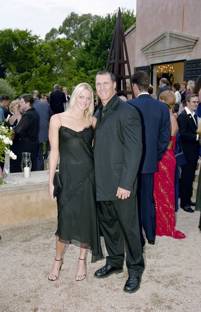 Princess Charlene in a black strappy dress and long hair with Andre Snyman