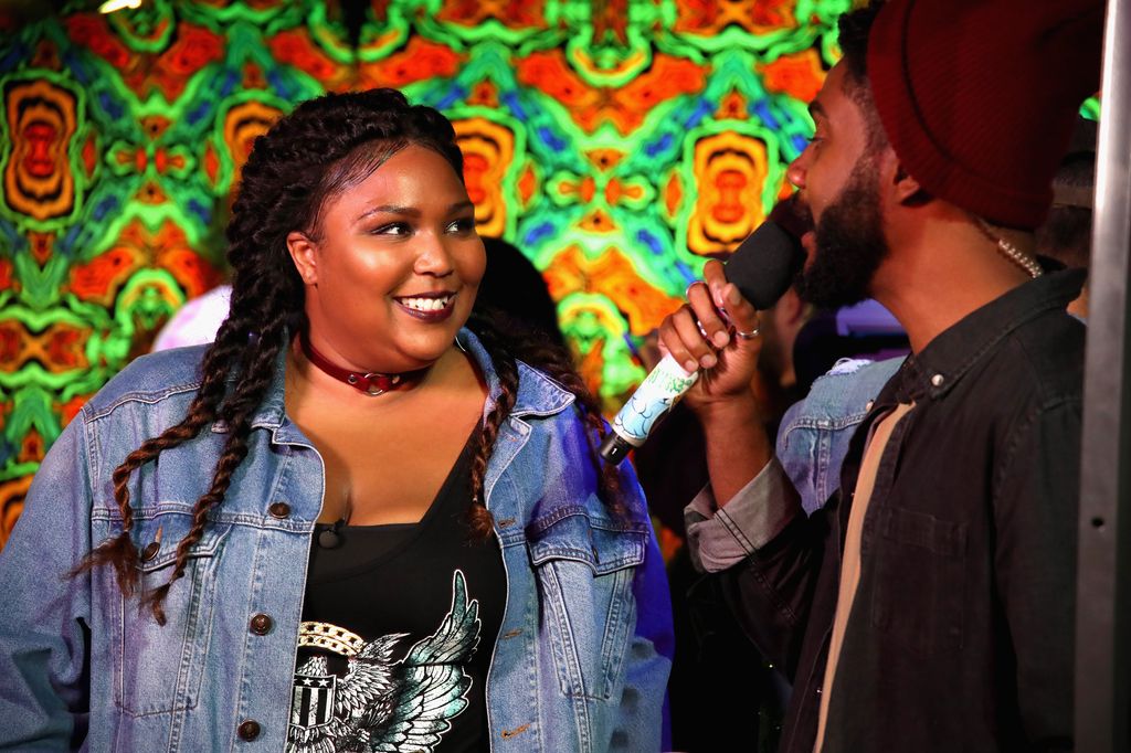 Myke speaking into microphone with Lizzo watching 
