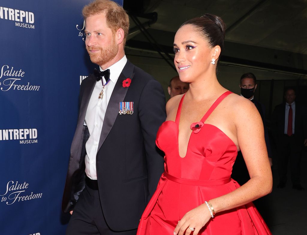 Prince Harry in a suit and Meghan Markle in a red dress