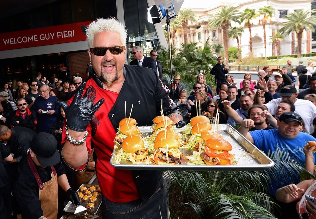 Chef and television personality Guy Fieri poses as he serves hamburgers to guests during a welcome event for Guy Fieri's Vegas Kitchen & Bar at The Quad Resort & Casino on April 4, 2014 in Las Vegas, Nevada. The restaurant opens on April 17. 