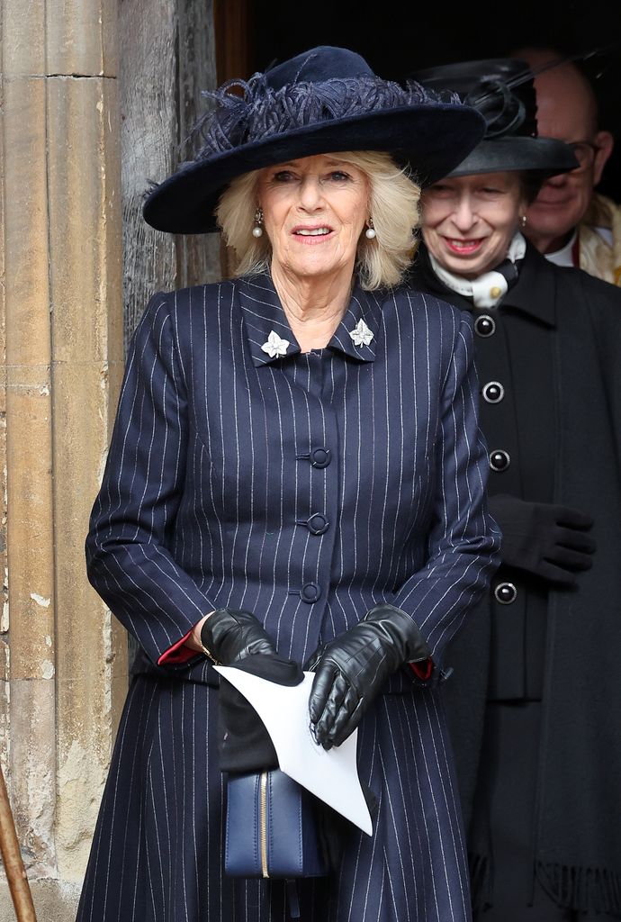 Queen Camilla in a pinstripe skirt suit and feathered hat