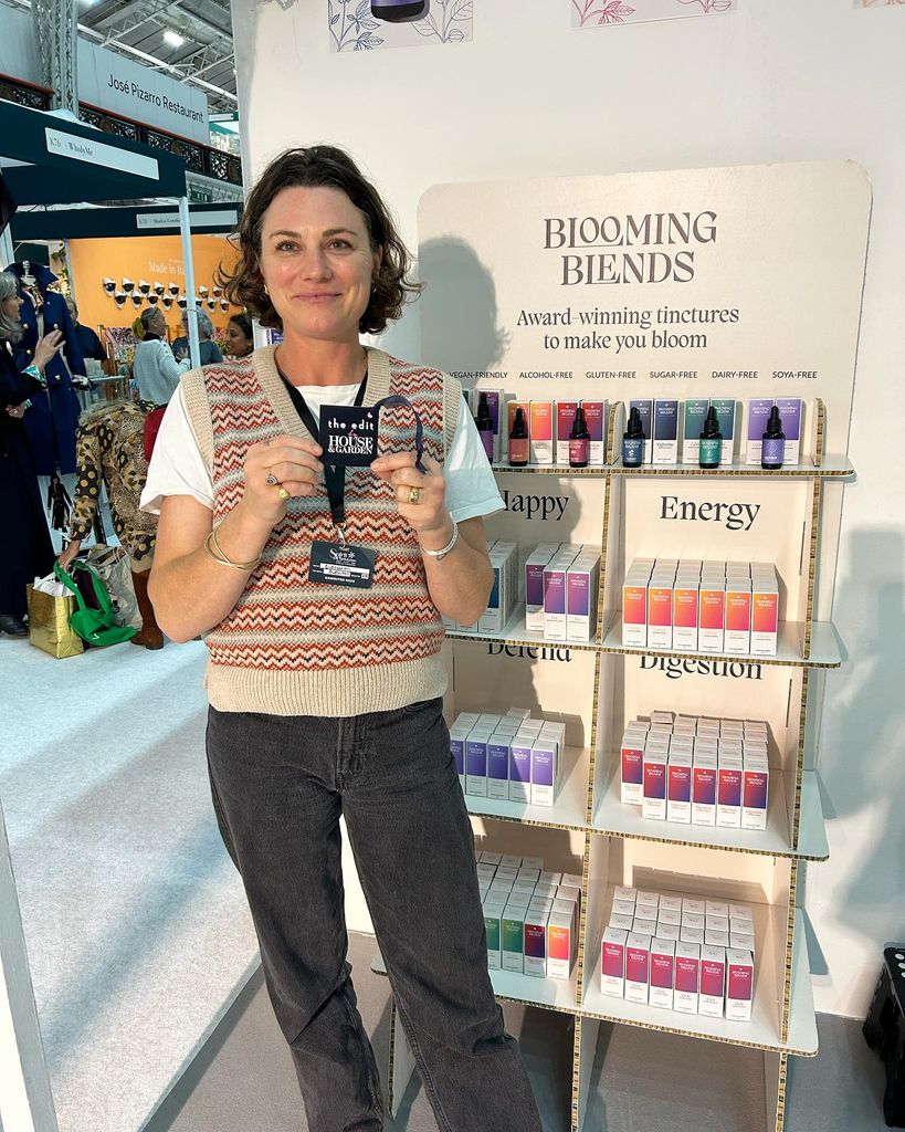 Woman holding a little card in front of a stand of tinctures 