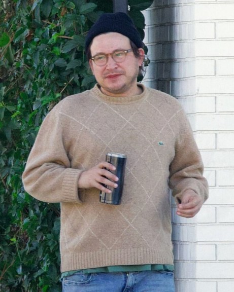 Jonathan Taylor Thomas wearing a jumper holding a flask