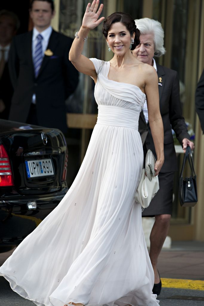 Crown Princess Mary Of Denmark waving in a white one-shoulder dress