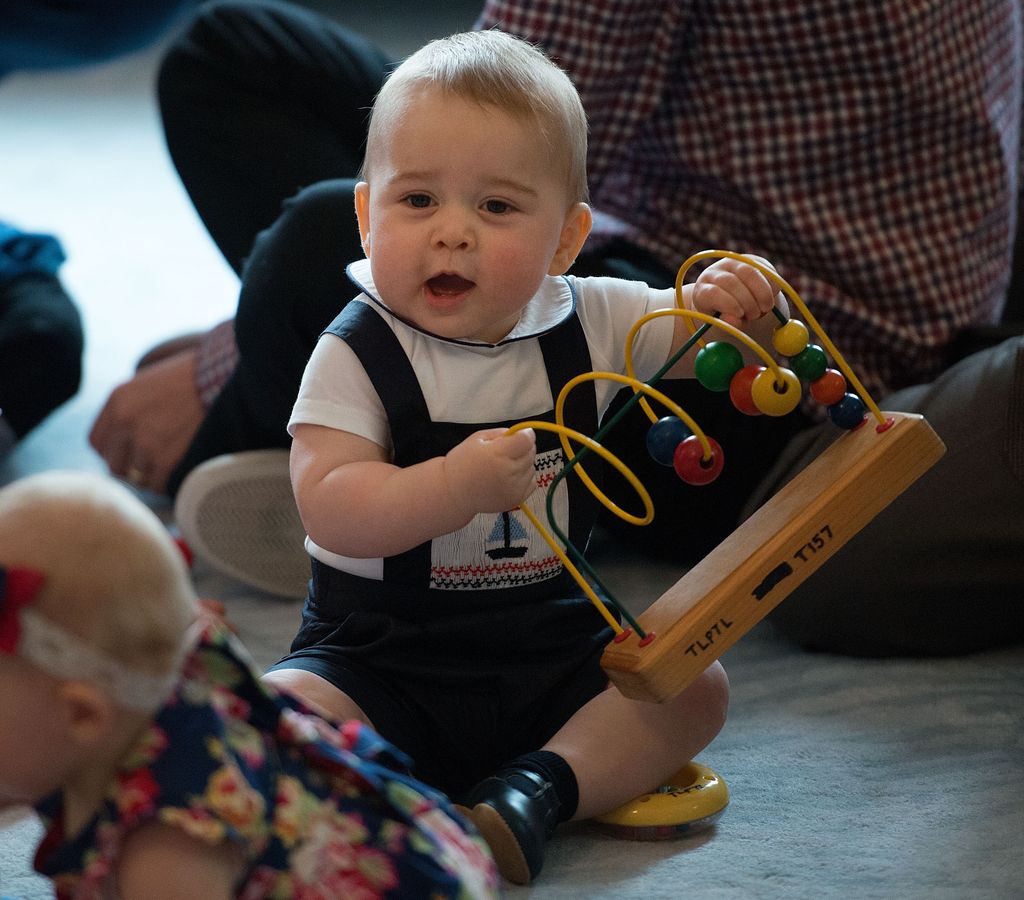 Bebê Príncipe George brincando com um ábaco