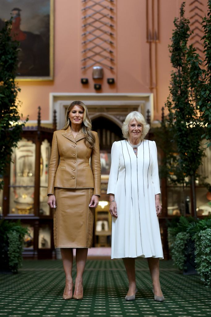 First Lady Melania Trump in beige leather skirt suit and Queen Camilla in white dress as they pose as they tour Queen Mary’s Dolls' House and the Royal Library at Windsor Castle.