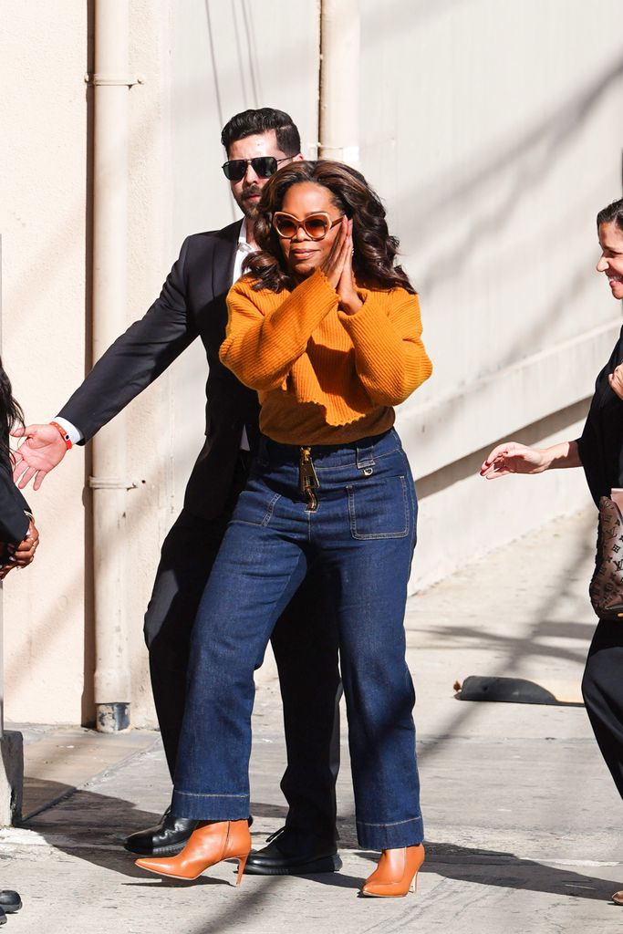 Oprah walking in dark jeans and sweater