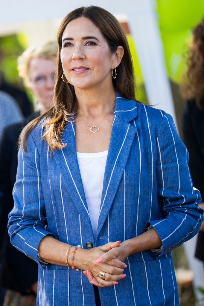 Queen Mary in blue pinstriped suit and gold earrings/necklace 