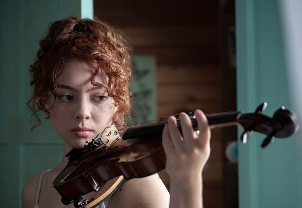 A curly haired girl playing the violin